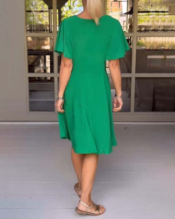 Enfärgad avslappnad klänning i midjan med V-ringning och fjärilsärm